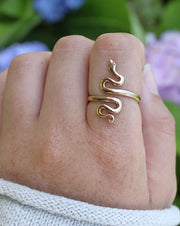 Adjustable Bronze Serpent Ring on pointer finger with flowers in back