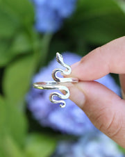 Adjustable Sterling Silver Serpent Ring between fingers with flowers in background