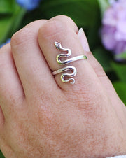 Adjustable Sterling Silver Serpent Ring on pointer finger with flowers in background