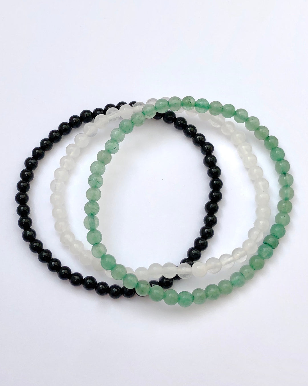 Aventurine, Snow Quartz and Black Agate beaded gemstone bracelets on white background.