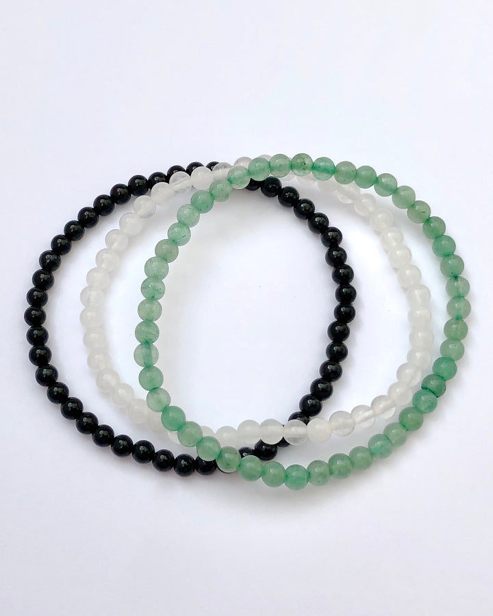 Aventurine, Snow Quartz and Black Agate beaded gemstone bracelets on white background.