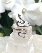 Adjustable Sterling Silver Serpent Ring on selenite stone with flowers in background