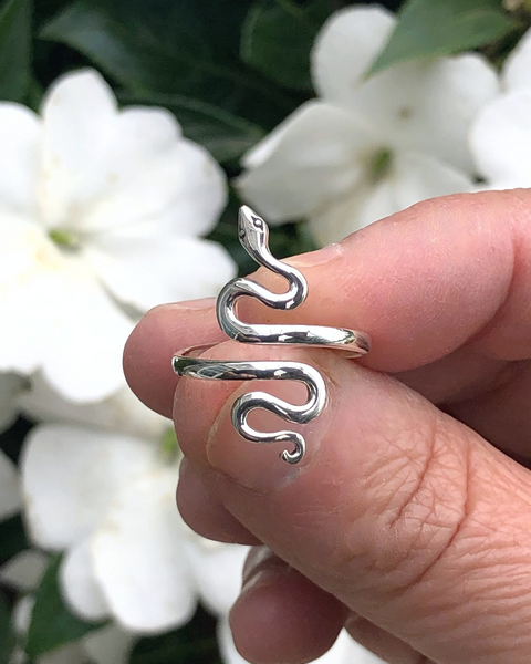 Adjustable Sterling Silver Serpent Ring between fingers with flowers in background