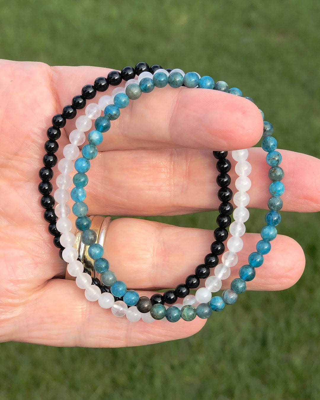 Apatite, Snow Quartz and Black Agate Bracelets in a hand