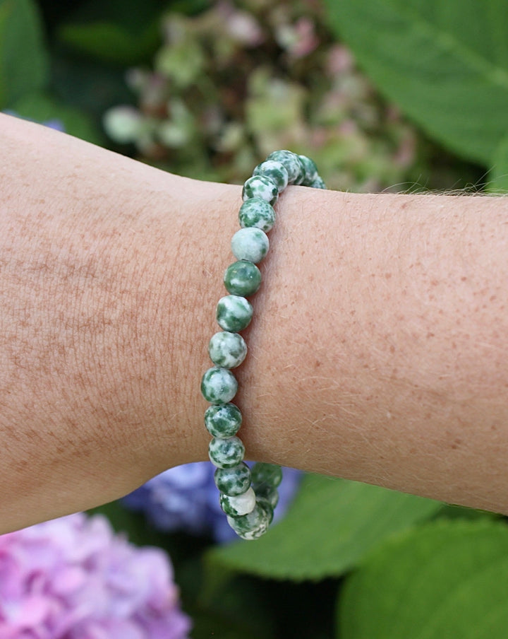 Natural Green Jade 6mm Beaded Gemstone Bracelet on a wrist with flowers.