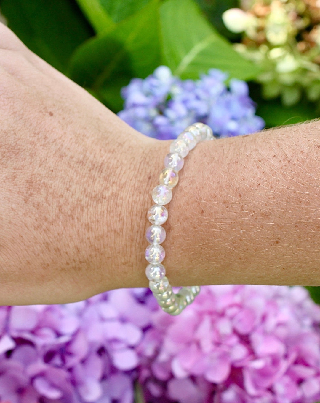 Angel Aura 6mm Beaded Gemstone Bracelet on a wrist with flowers