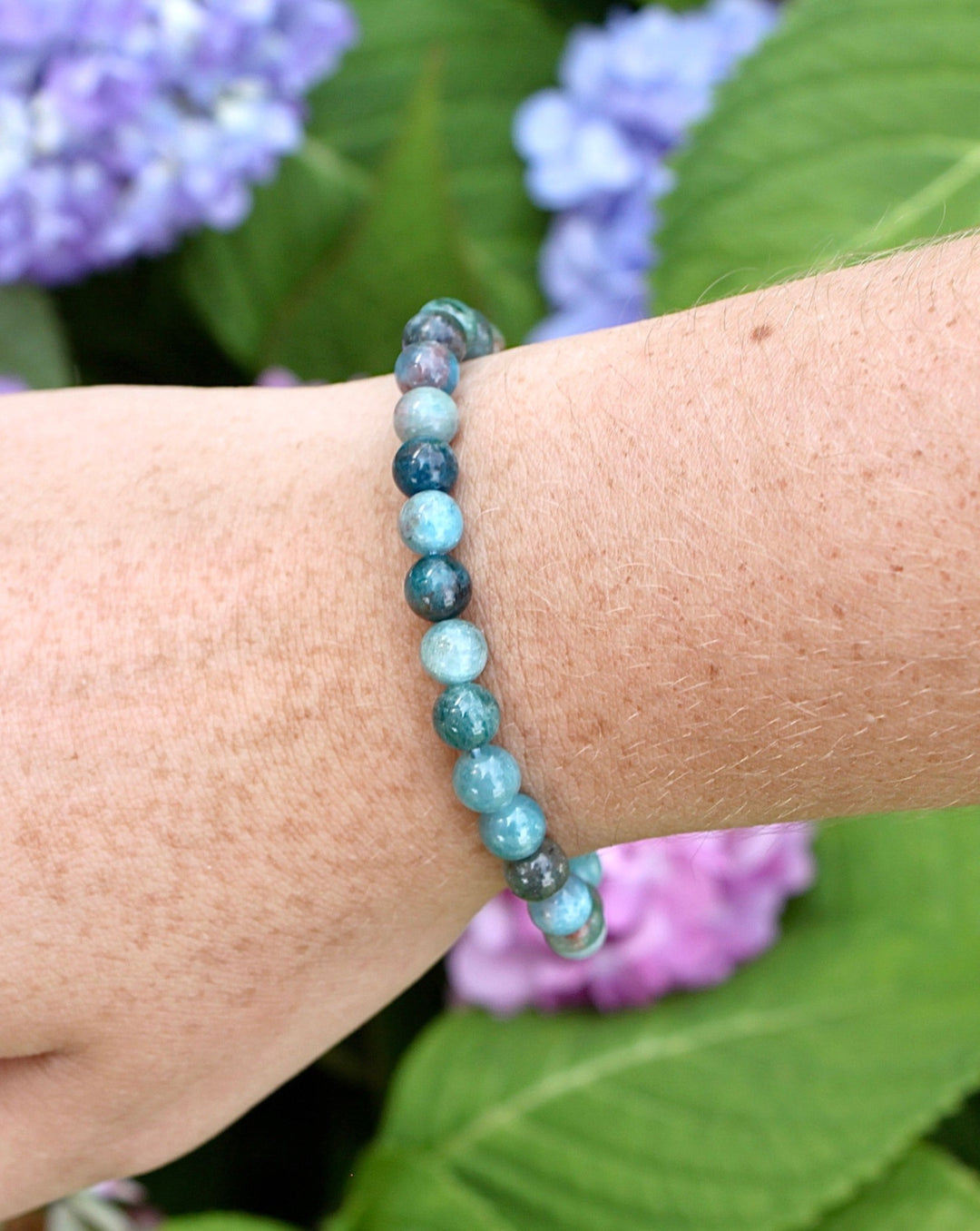 Apatite 6mm Beaded Gemstone Bracelet on a wrist with flowers