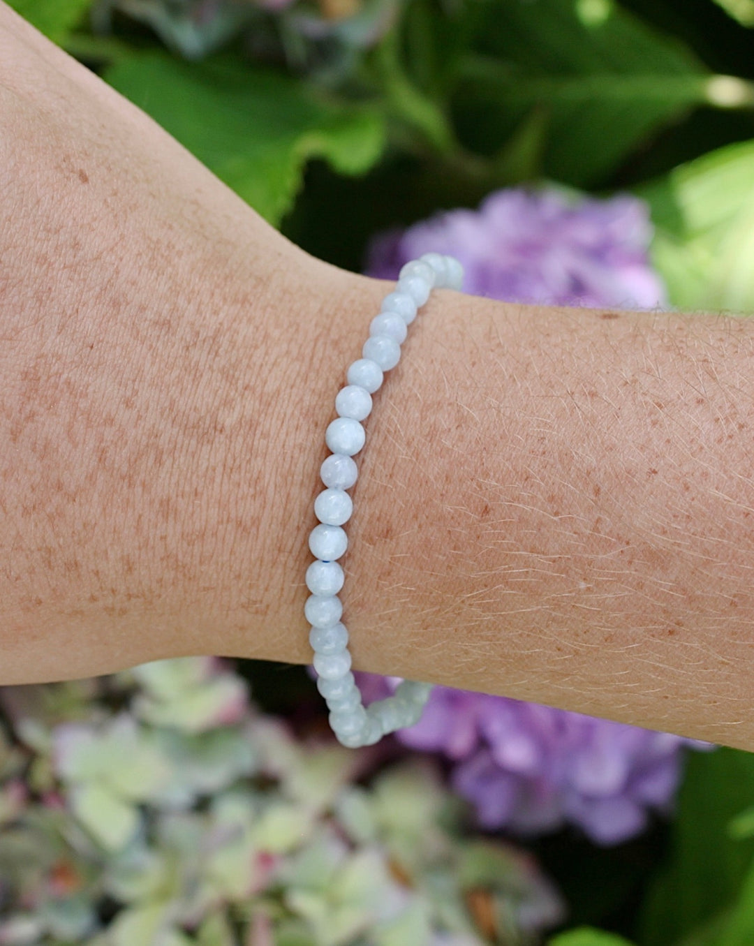 Aquamarine 4mm beaded gemstone bracelet on a wrist.