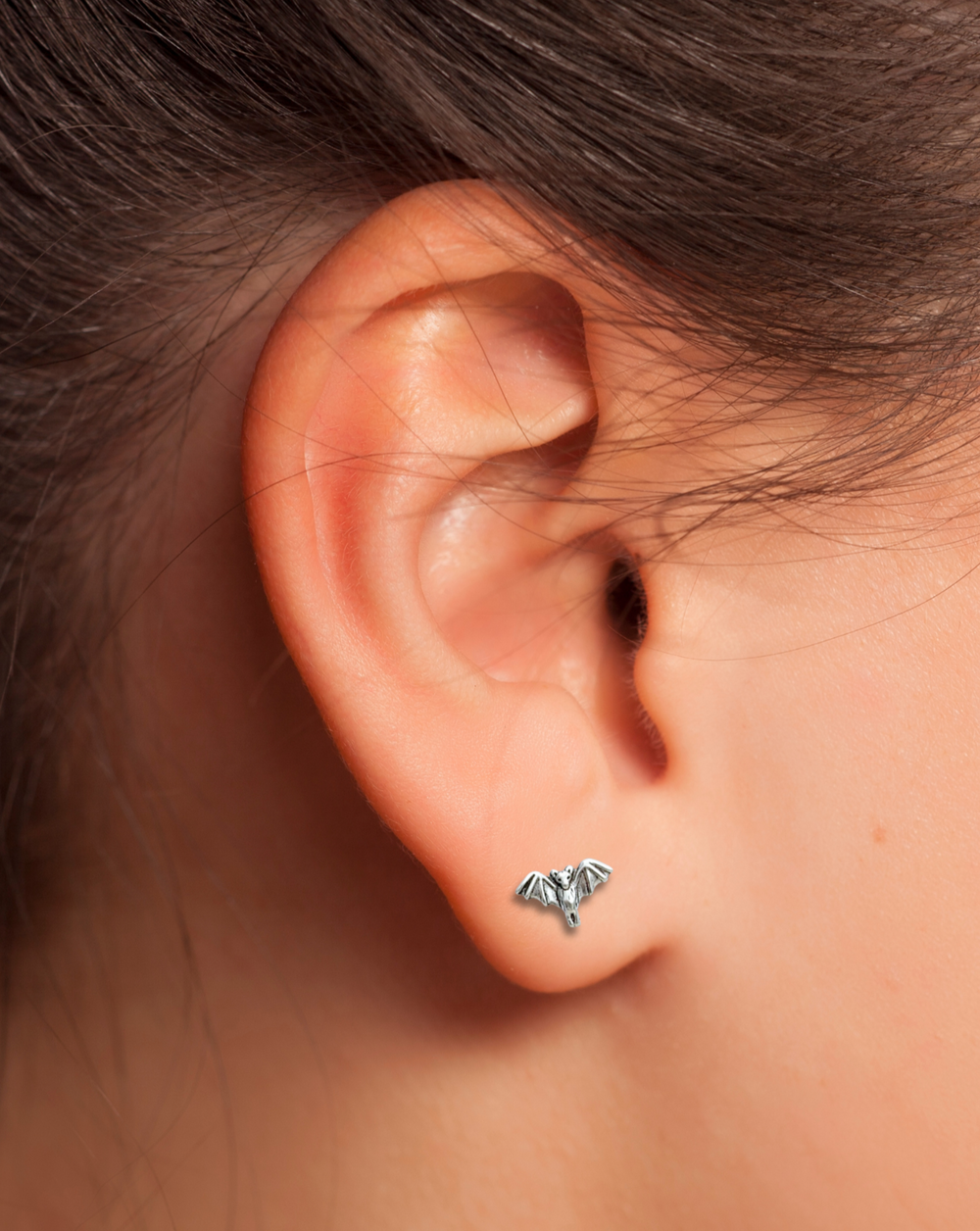 Sterling Silver Tiny Bat Stud Earring on an ear.