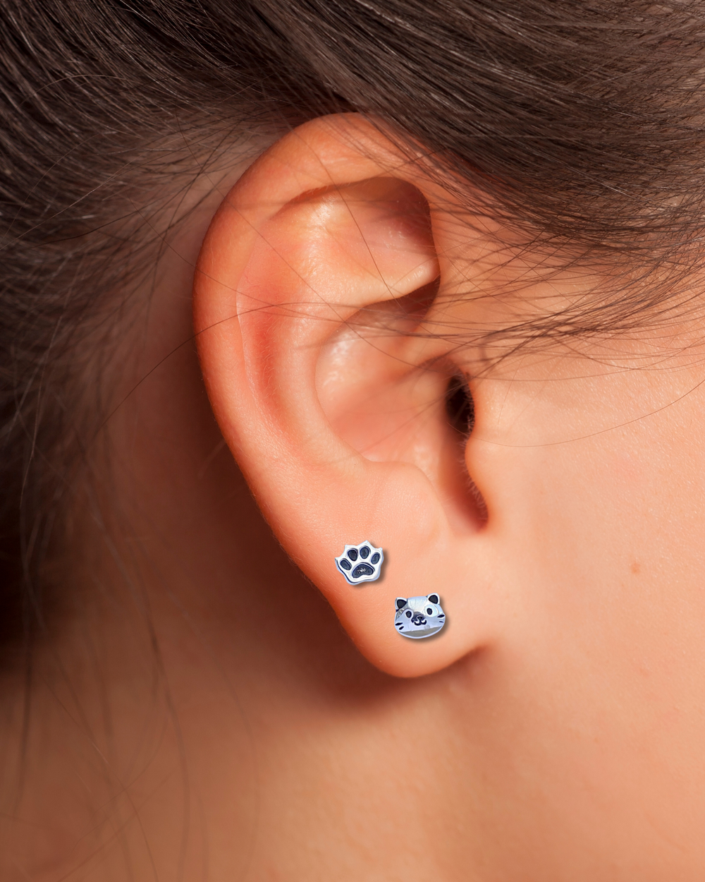 Cat Face and Paw Print Sterling Silver Stud Earrings on an ear.