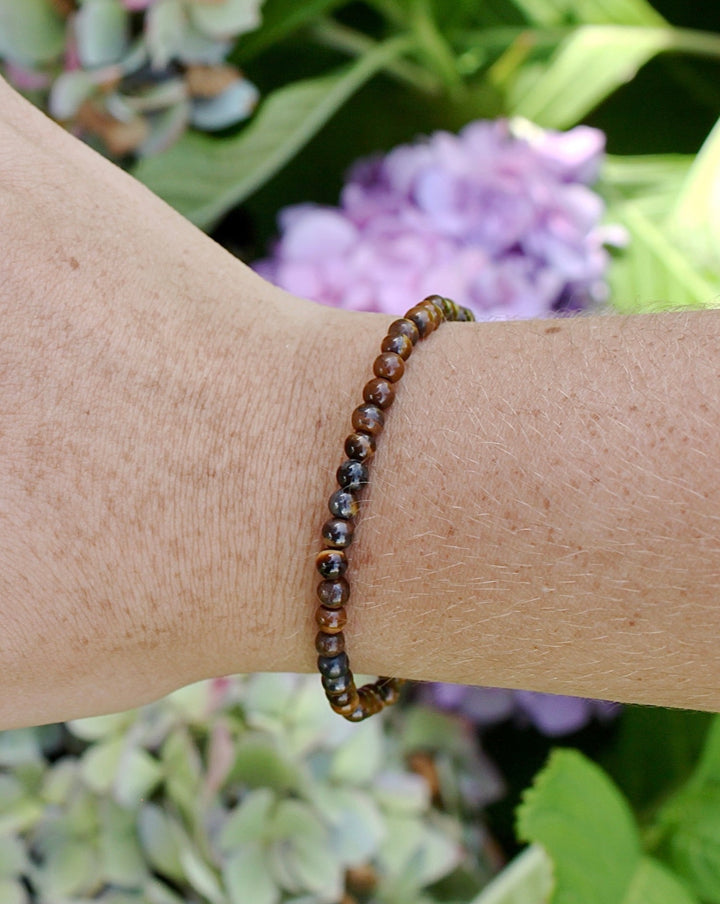 Children's Tiger Eye 4mm Gemstone Bracelet on a wrist with background flowers