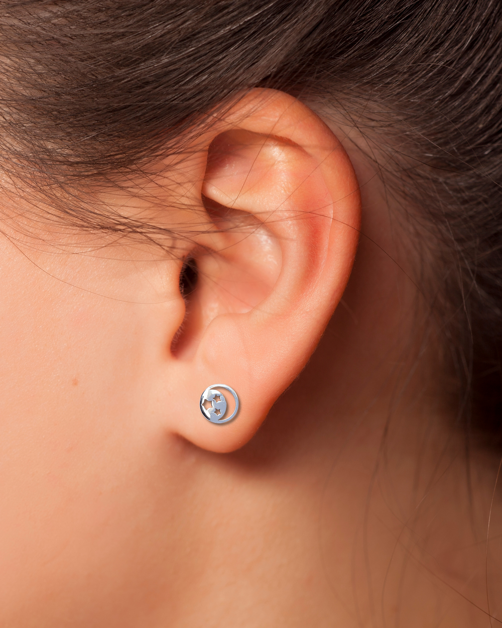 Crescent Moon and Stars Silver Earrings on an Ear.