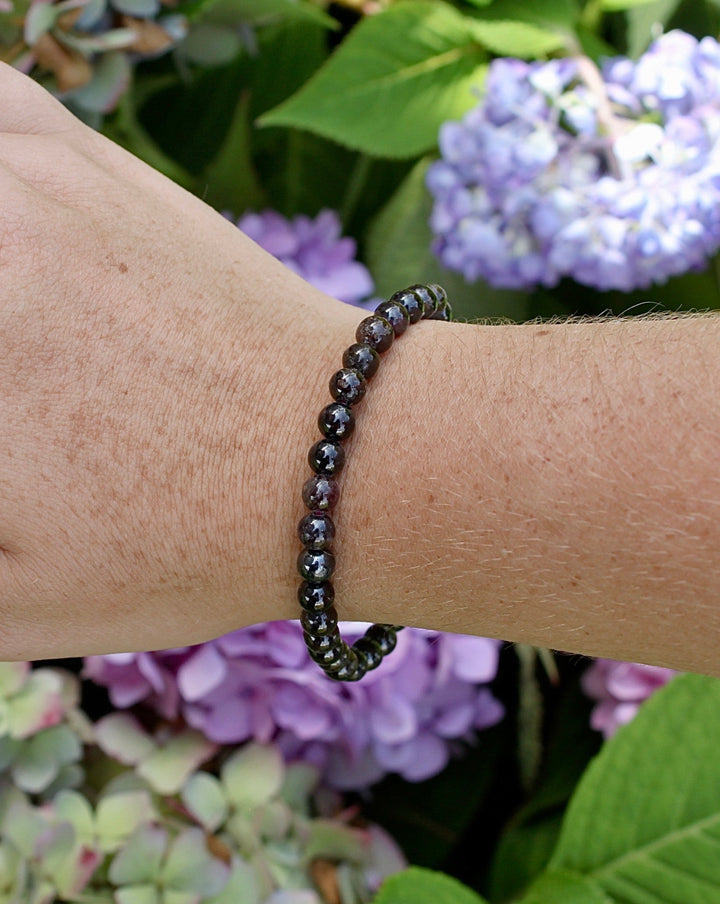 Garnet 6mm Beaded Gemstone Bracelet on a wrist with flowers