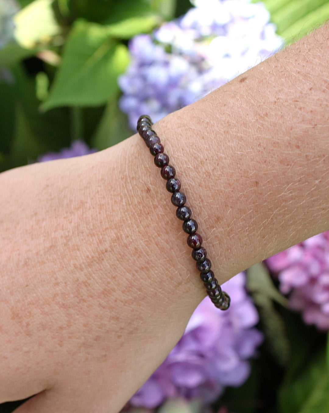 Garnet 4mm Beaded Gemstone Bracelet on a wrist with flowers