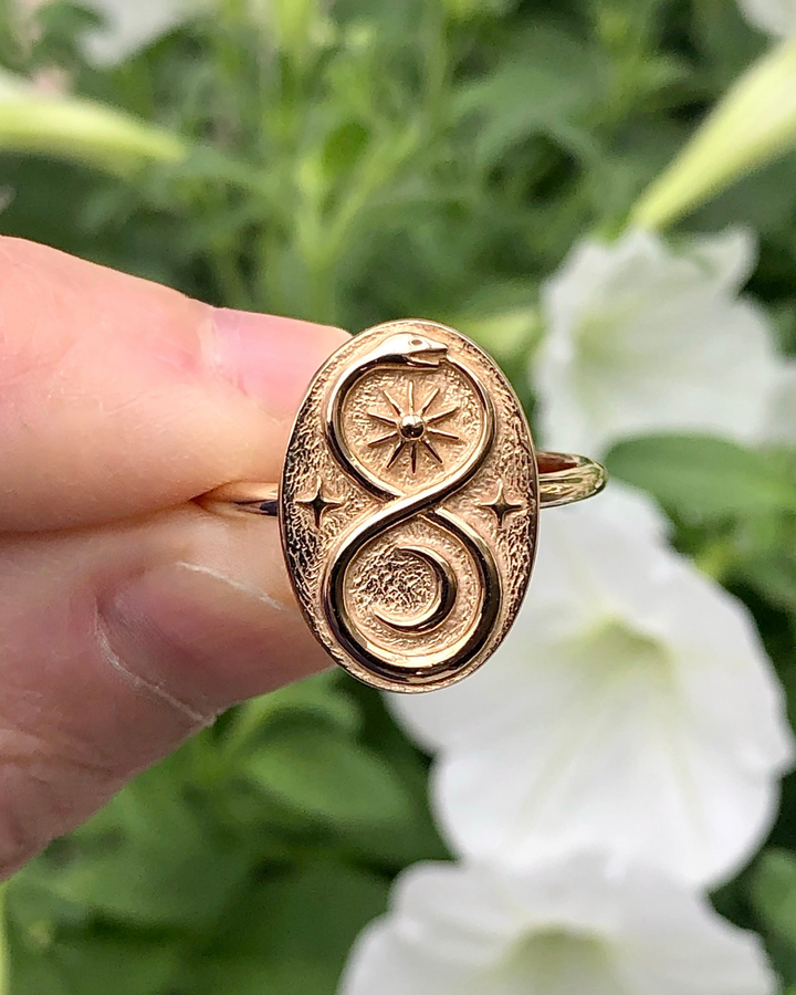 Bronze Ouroboros Ring close up between fingers