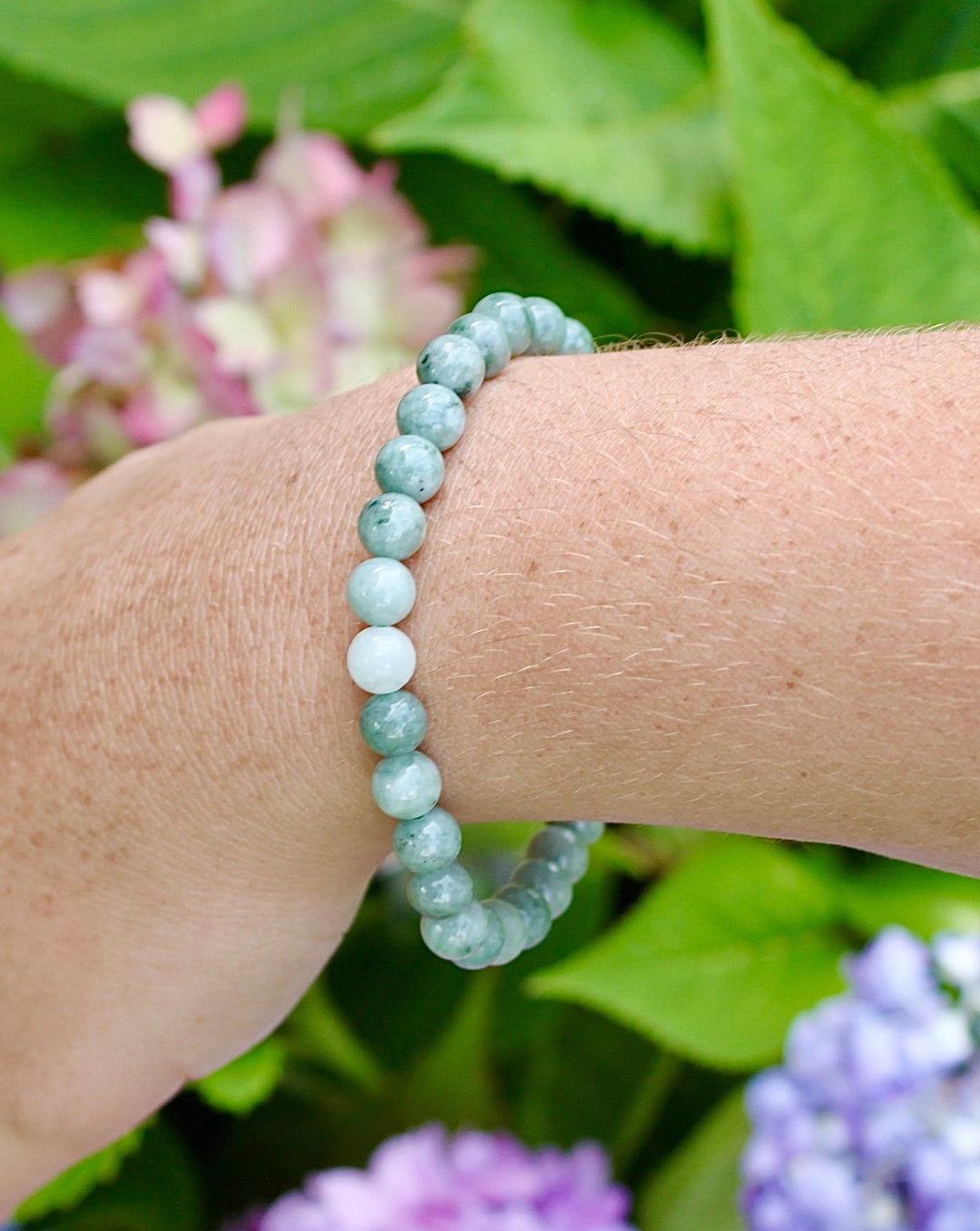 Jadeite 6mm Beaded Gemstone Bracelet on a wrist with flowers