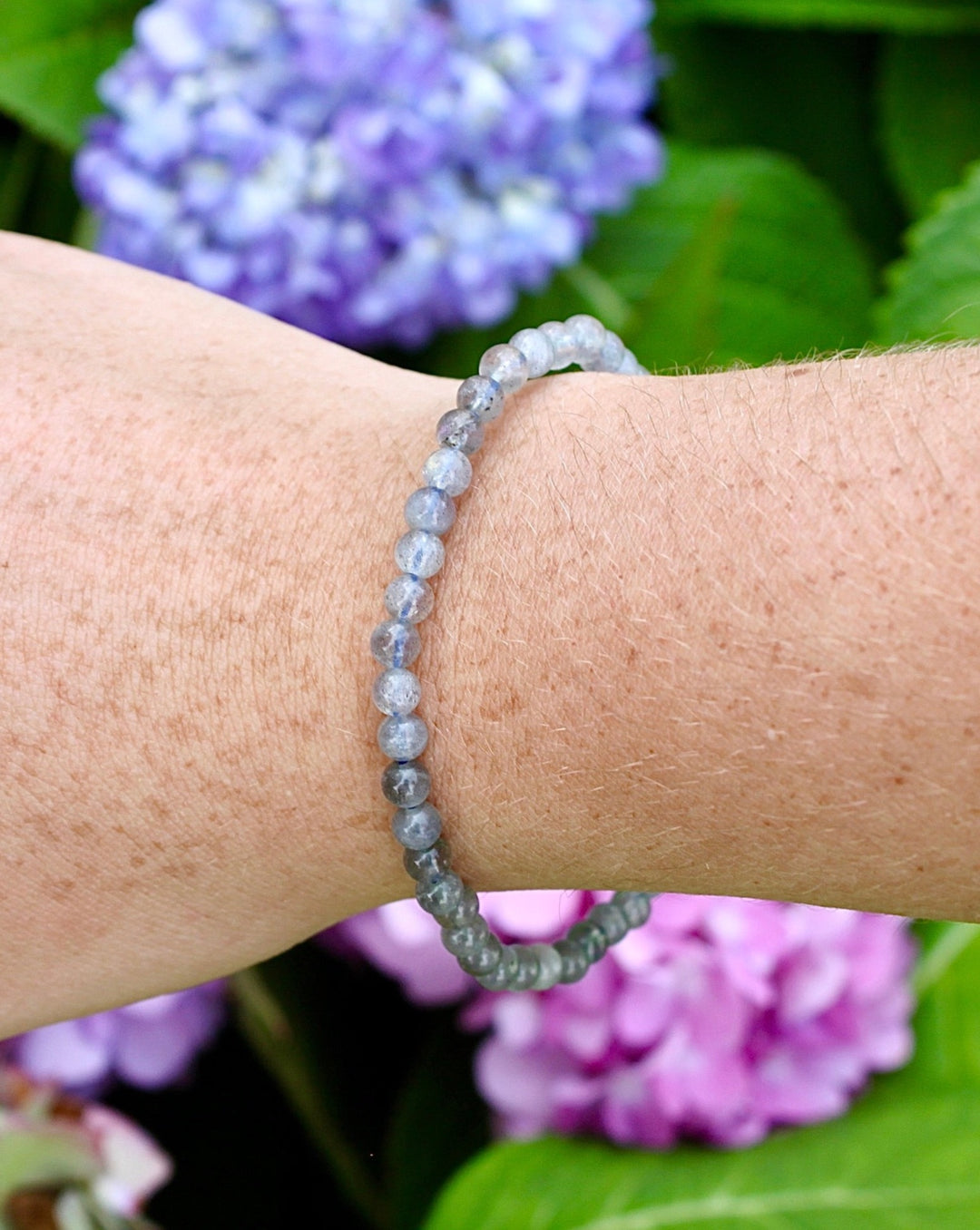 Labradorite 4mm Beaded Gemstone Bracelet on a wrist with flowers.