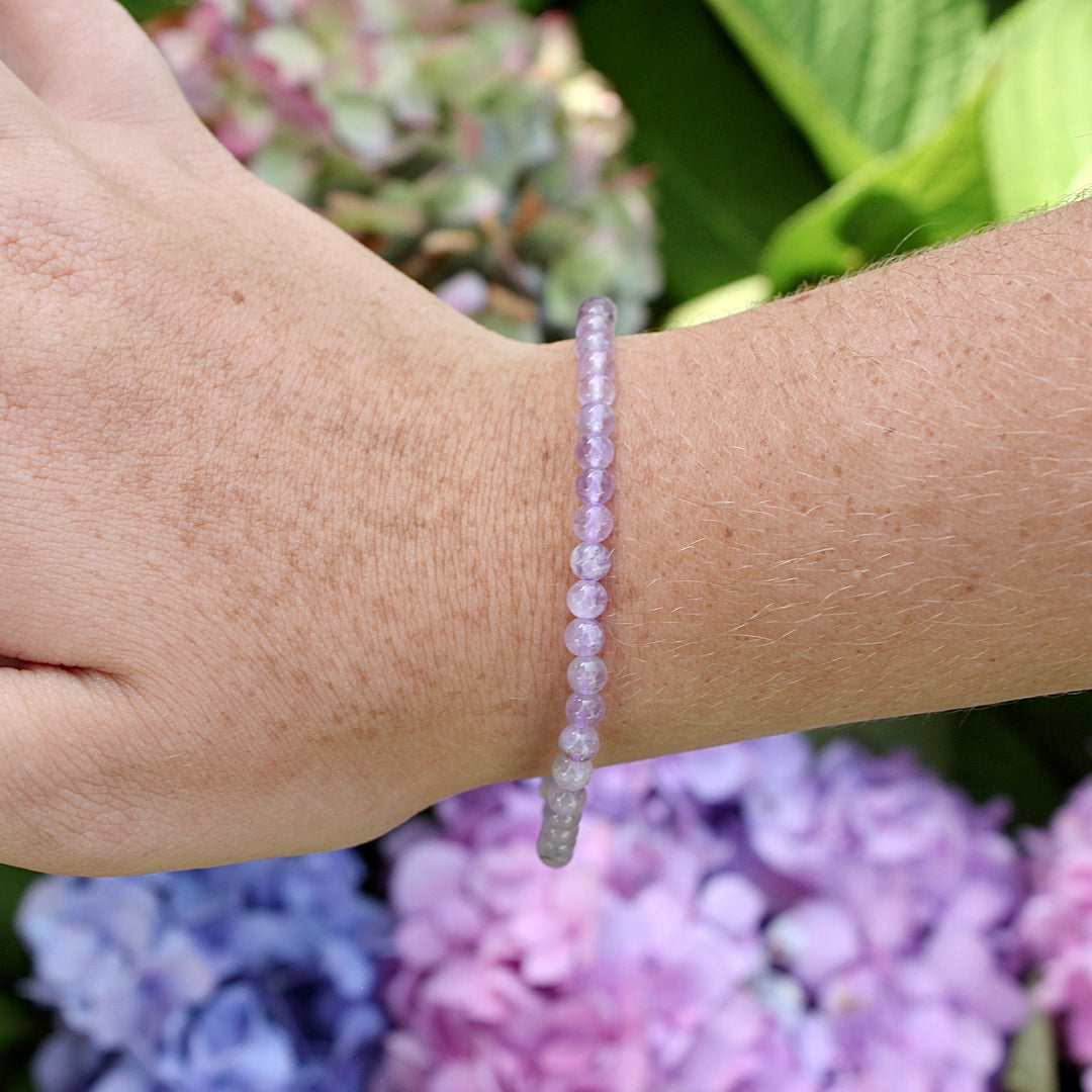 Children's Lavender Amethyst 4mm Gemstone Bracelet on a wrist with flowers