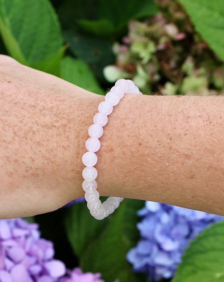 Moonstone 6mm Beaded Gemstone Bracelet on a wrist with flowers.