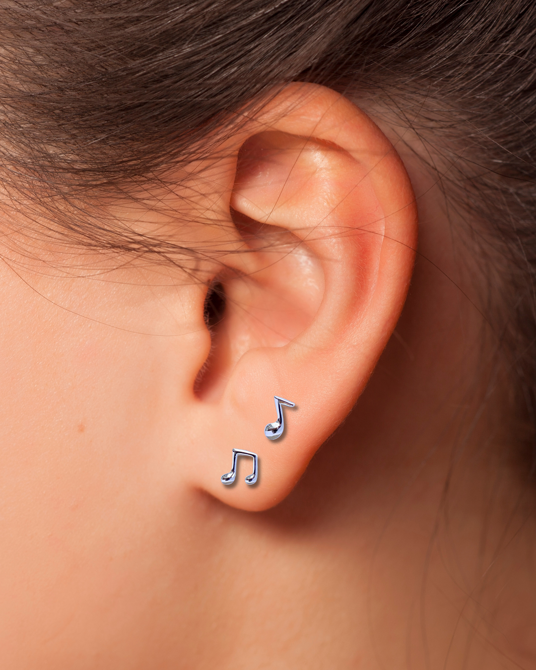 Music Note Silver Earrings on an Ear.