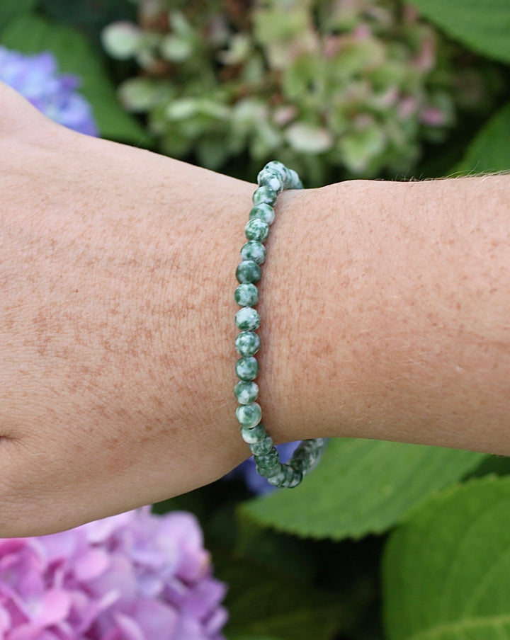 Natural Green Jade 4mm Beaded Gemstone Bracelet on a wrist with flowers.