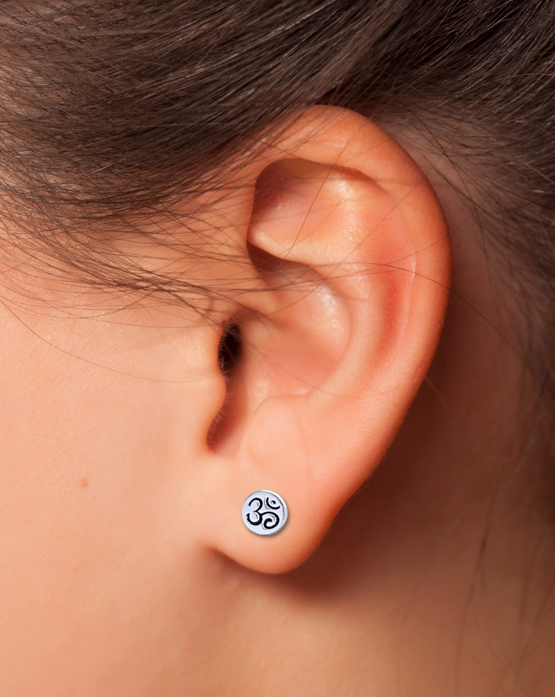 Om Sterling Silver Earring on an Ear.