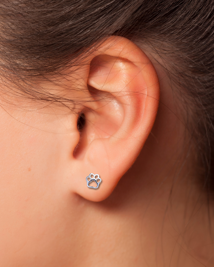 Paw Print Cutout Silver Earring on an ear.