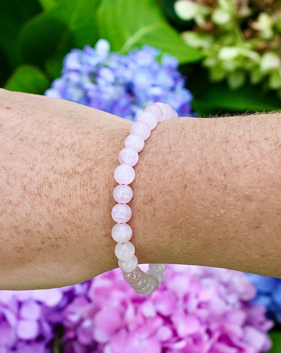 Rose Quartz 6mm Beaded Gemstone Bracelet on a wrist with flowers.