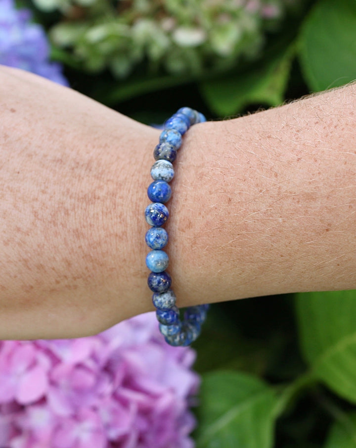 Sodalite 6mm Beaded Gemstone Bracelet on a wrist with flowers.