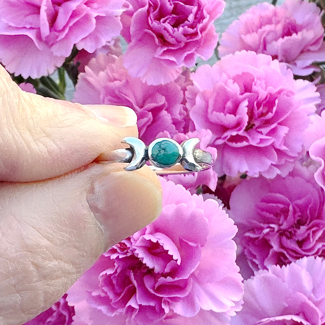 Sterling Silver Turquoise Moon Ring between fingers with pink flowers