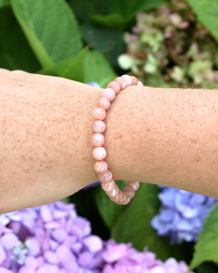 Sunstone 6mm Beaded Gemstone Bracelet on a wrist with flowers