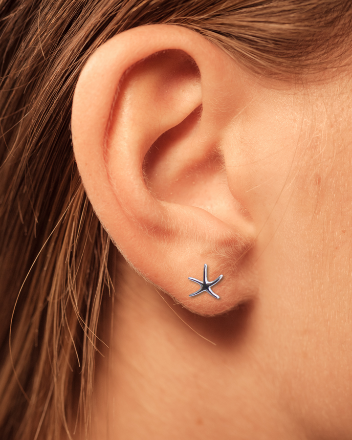 Thin Starfish Sterling Silver Earring on an ear.