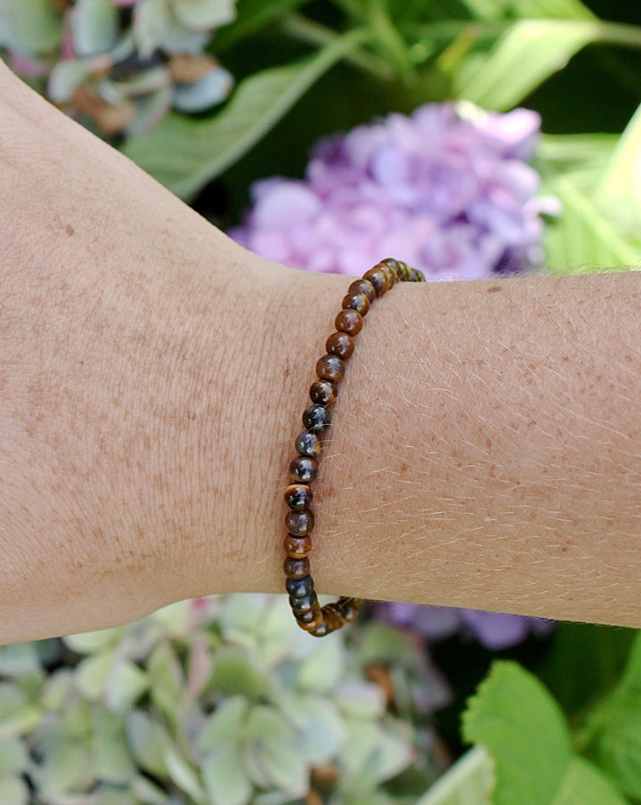 Tiger Eye 4mm Beaded Gemstone Bracelet o a wrist with background flowers