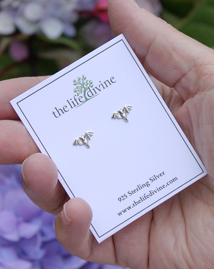 Tiny Bat Stud Earrings on a card held in a hand.