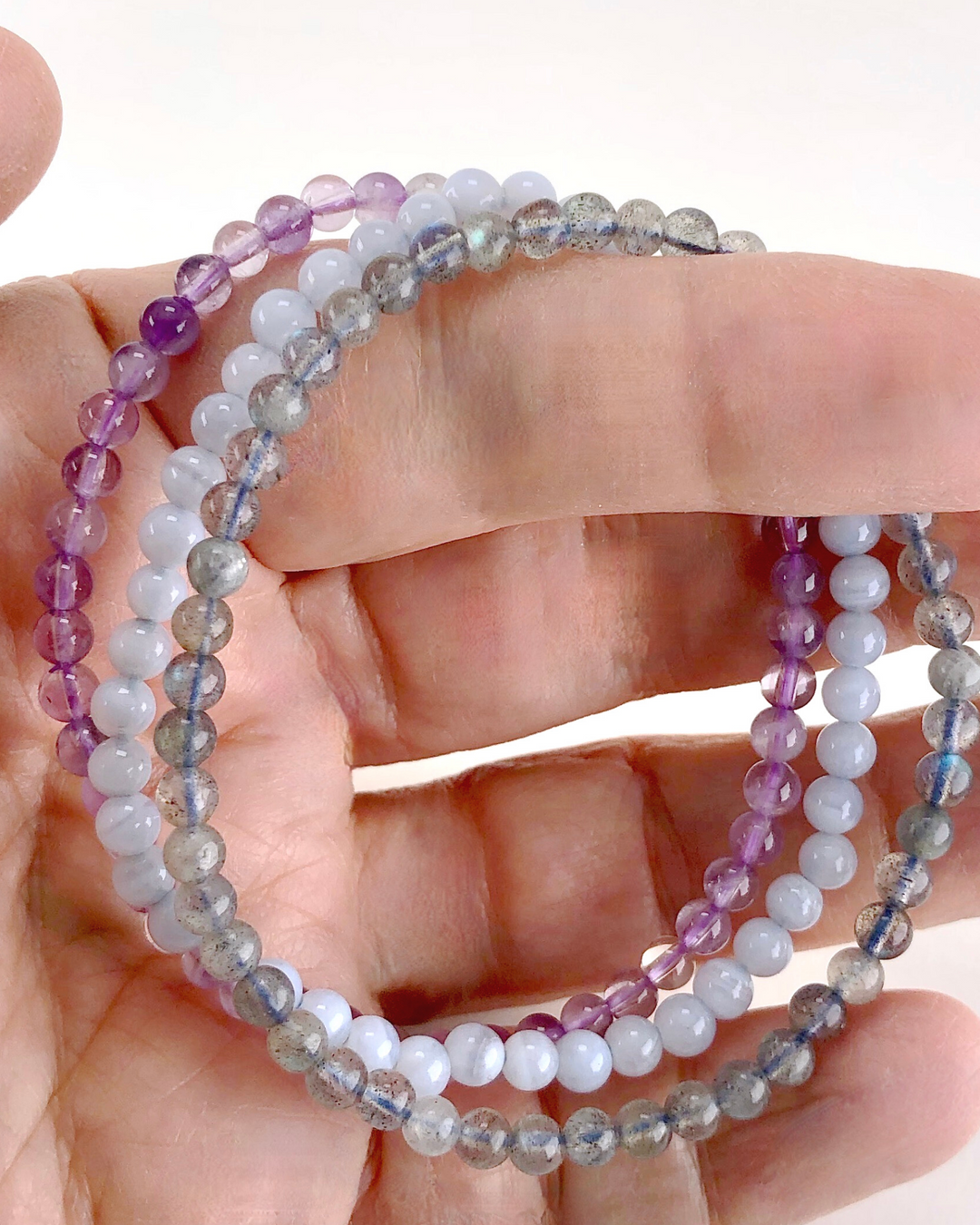 Blue Lace Agate, Lavender Amethyst and Labradorite 4mm beaded gemstone bracelet set for Anxiety Relief in a hand.