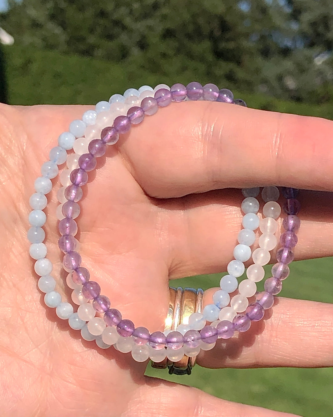 Lavender Amethyst, Snow Quartz and Aquamarine crystal Bracelets in a hand