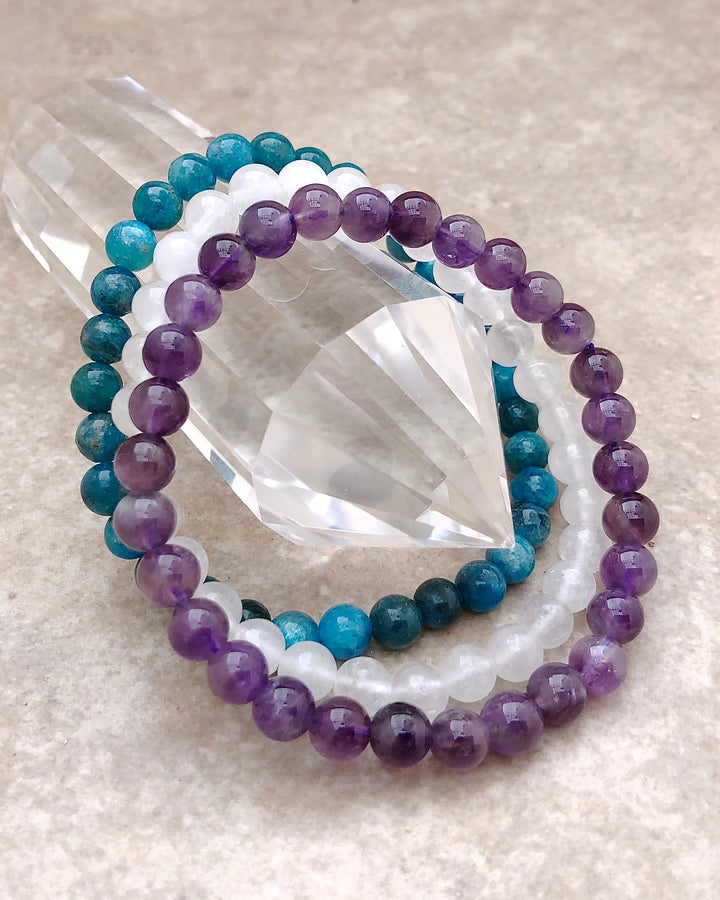 Amethyst, Snow Quartz and Apatite 6mm Beaded Gemstone Bracelet Set for Balance and Clarity on a crystal.