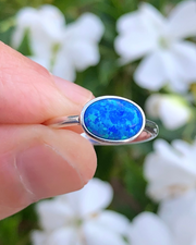 Sterling Silver Oval blue lab opal ring  being held between fingers