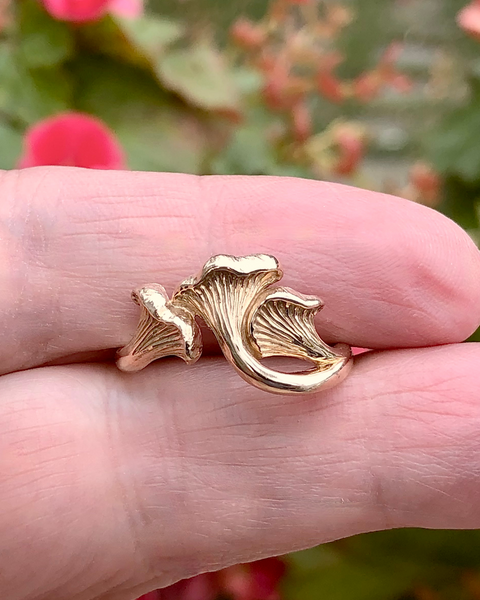 Bronze Chanterelle mushroom ring held between two fingers inside hand