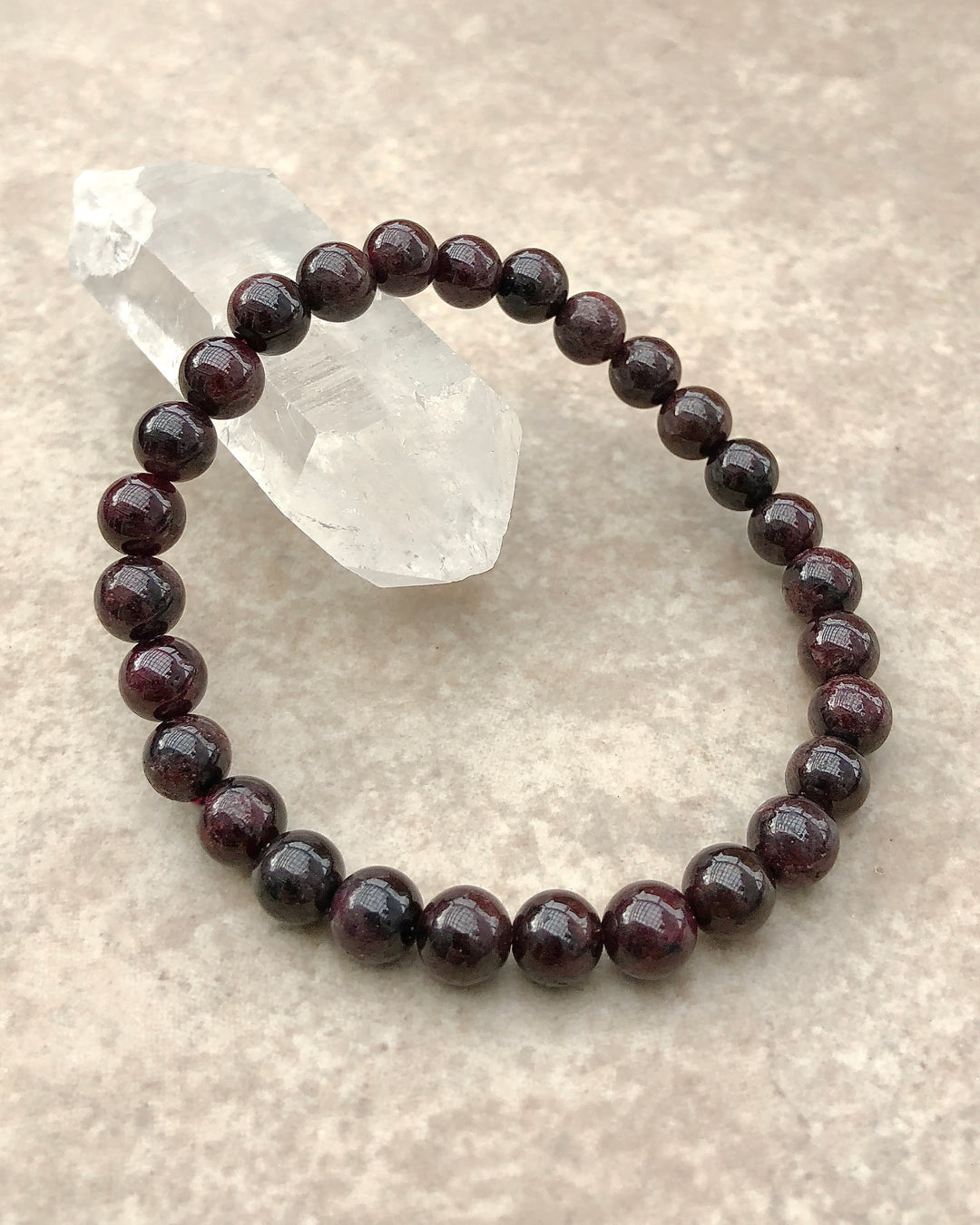 Garnet 6mm Beaded Gemstone Bracelet on a crystal.