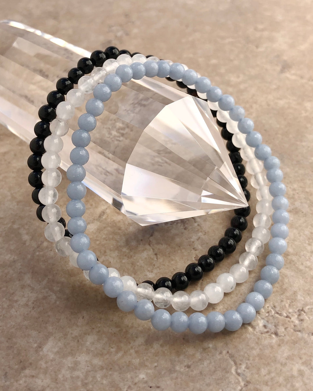 Aquamarine, Snow Quartz and Black Agate bracelets on a crystal