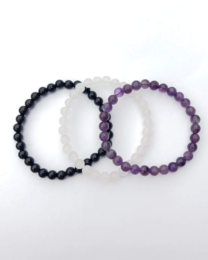 Amethyst, Snow Quartz and Black Agate 6mm Beaded Gemstone Bracelet Set for Inner Peace on a white background.