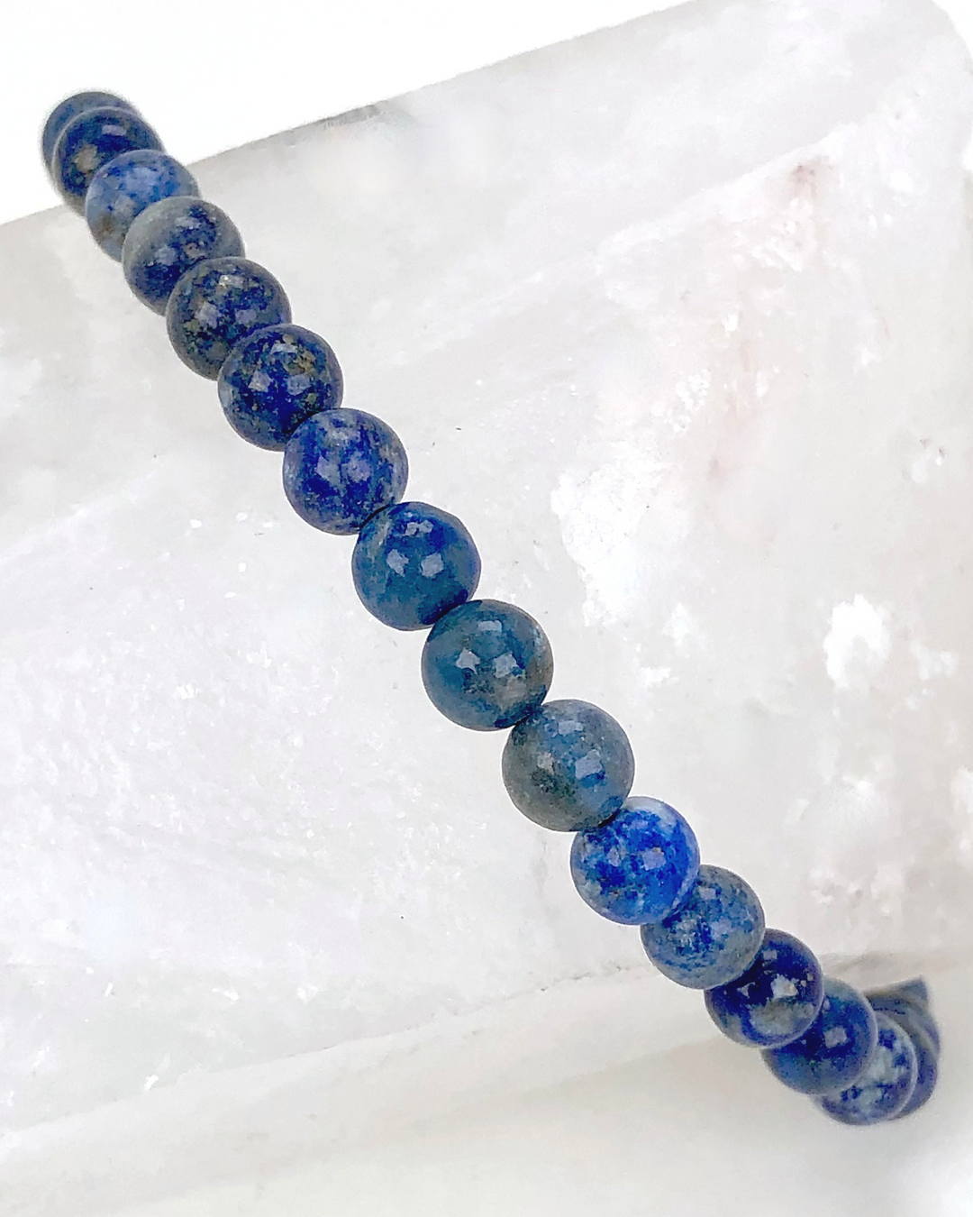 Lapis Lazuli 6mm Beaded Gemstone Bracelet around a crystal.