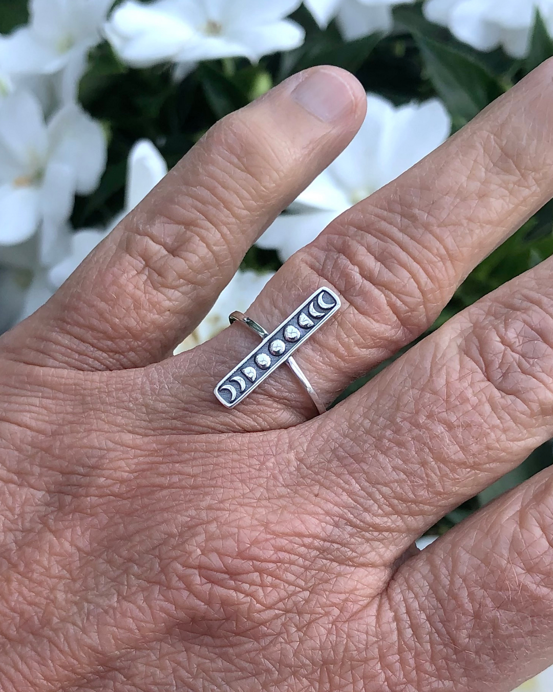 Moon Phases Bar Design Sterling Silver Ring on a finger with flowers