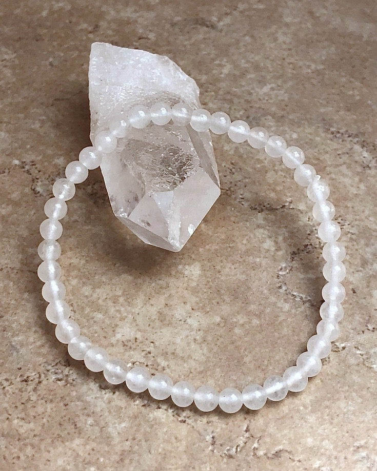 Men's Snow Quartz 4mm Beaded Gemstone Bracelet on a crystal.