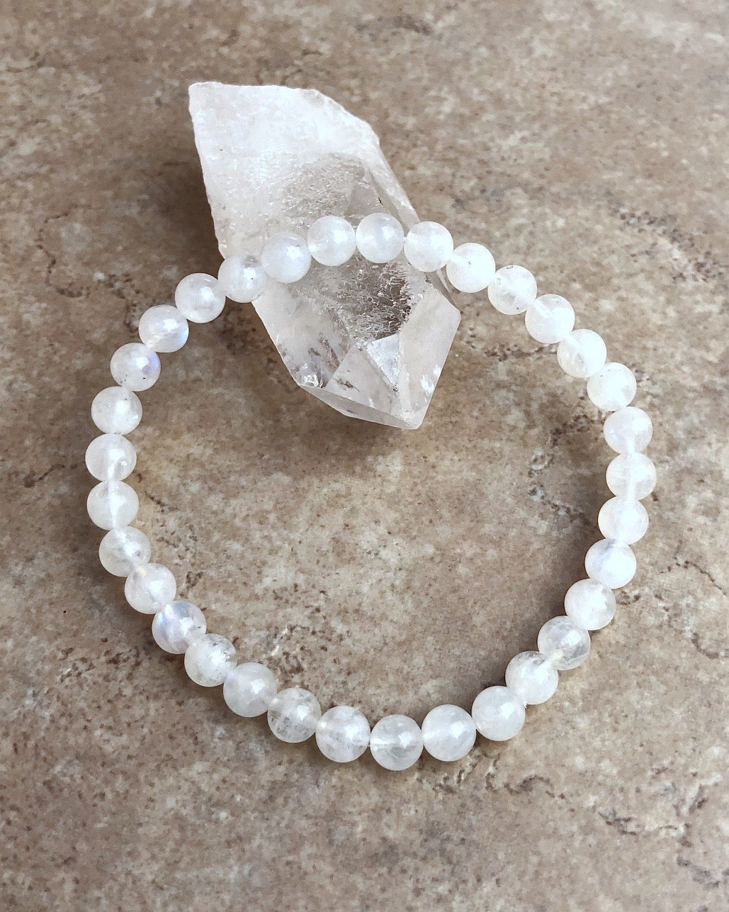 Moonstone 6mm Beaded Gemstone Bracelet on a crystal.