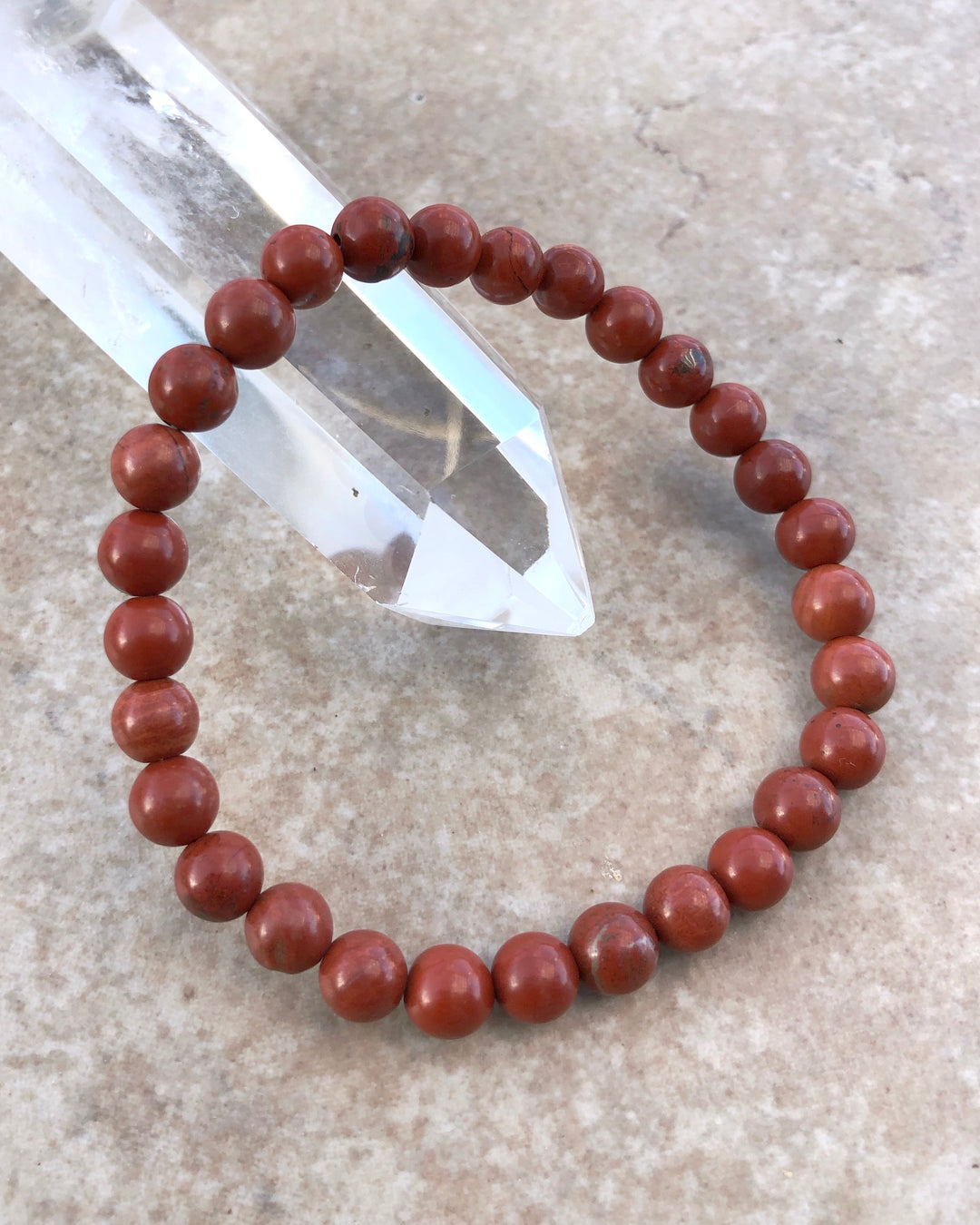 Red Jasper 6mm Beaded Gemstone Bracelet on a crystal.