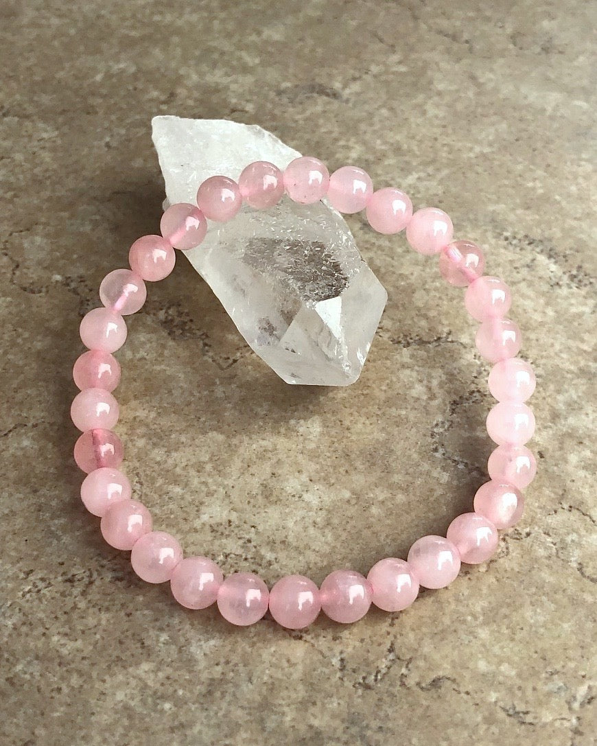 Rose Quartz 6mm Beaded Gemstone Bracelet on a crystal.