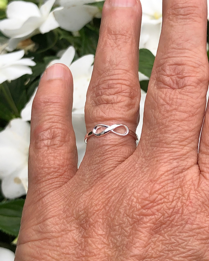 Silver Infinity Ring on ring finger with white flowers