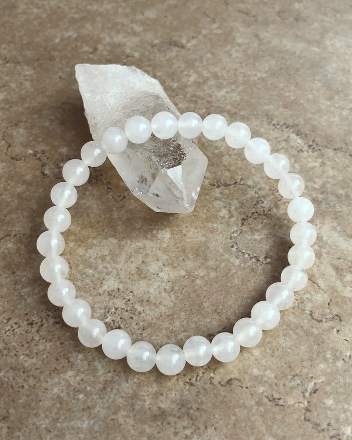 Snow Quartz 6mm Beaded Gemstone Bracelet on a crystal.